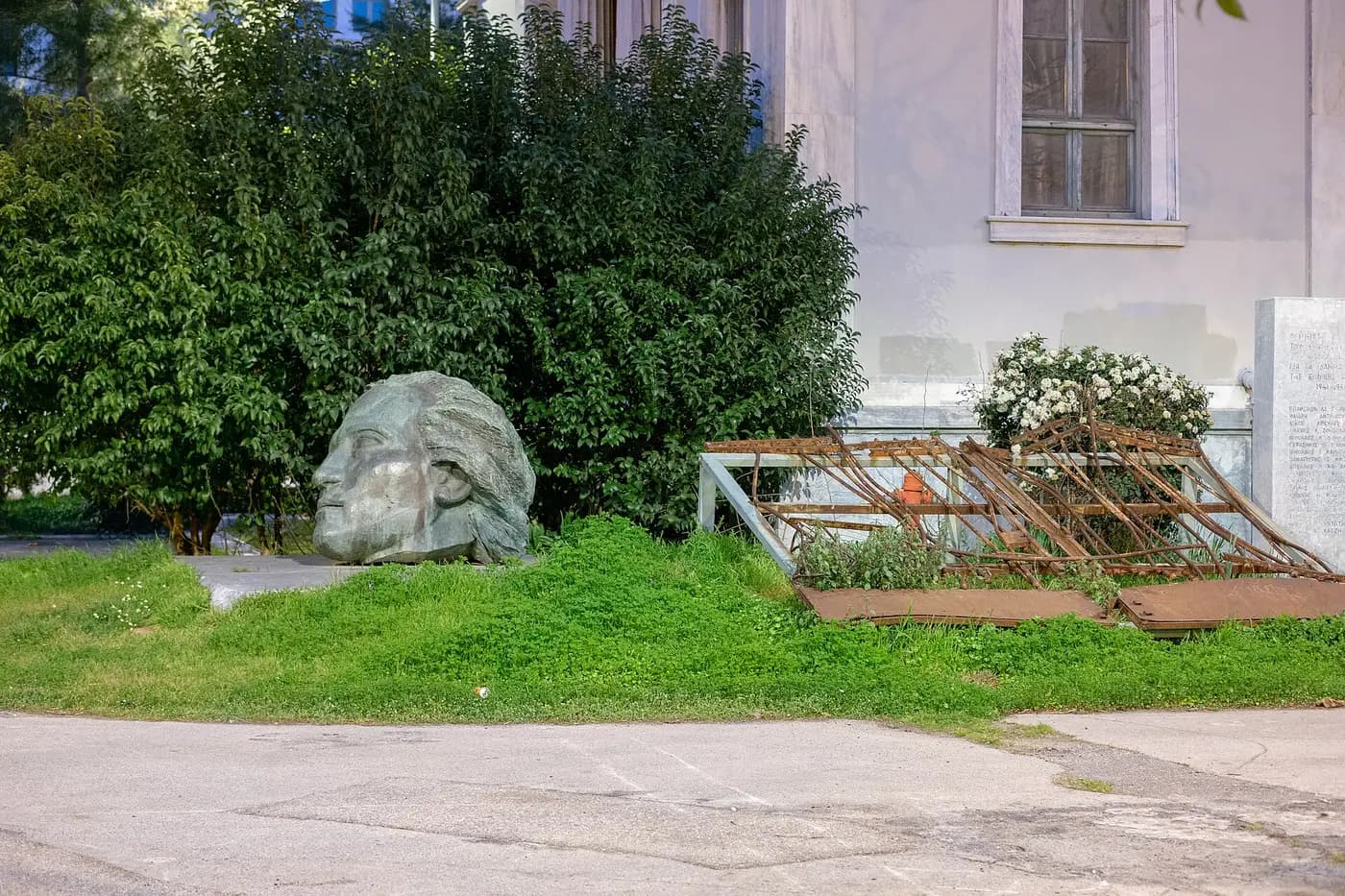 The crushed iron gate of the Athens Polytechnic beside Memos Makris's sculpted head memorial